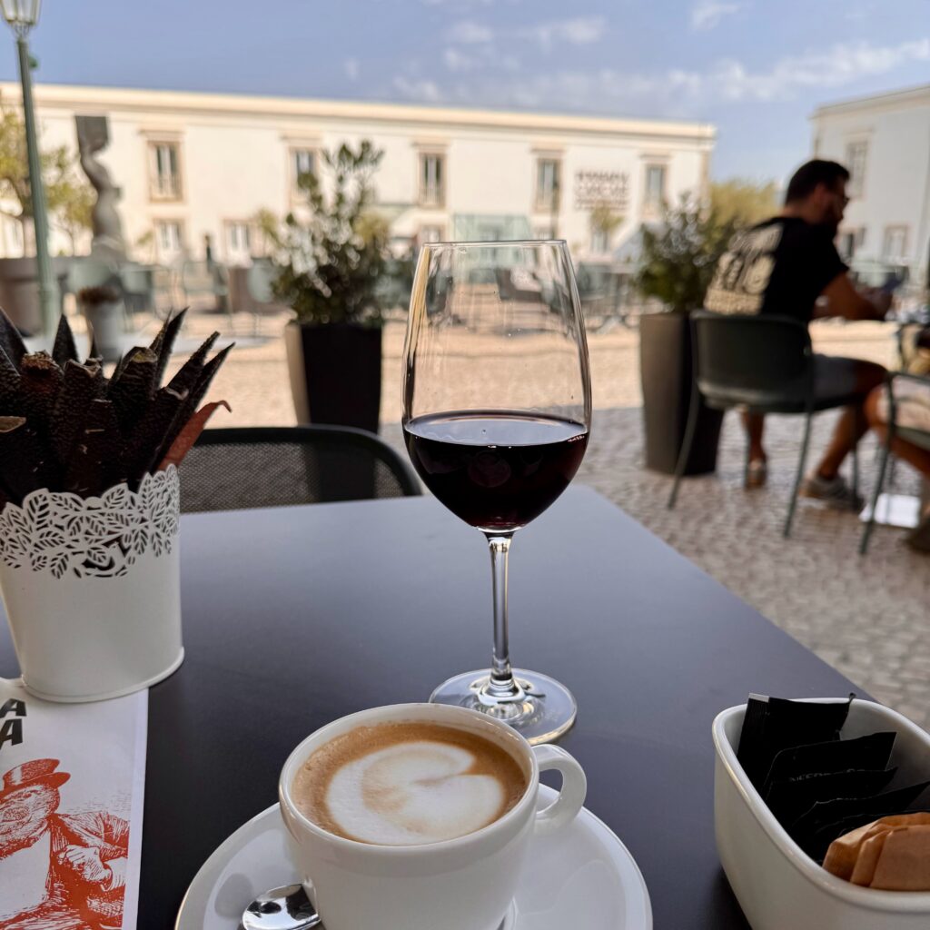 Photo of a terrace café at a Portugal small hotel, with a glass of red wine and a cappuccino served al fresco under the Algarve sun.