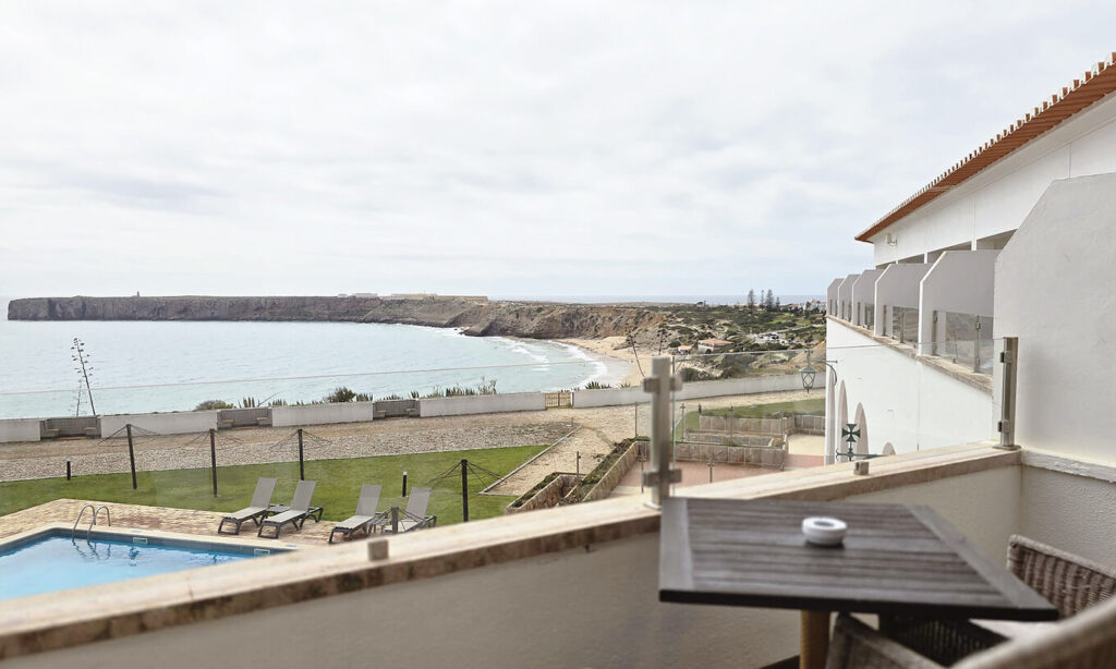 Guests relaxing by an infinity pool at a Portugal small hotel, with terracotta rooftops and palm trees in the background.
Image source and rights Pestana
https://www.pousadas.pt/es/hotel/pousada-sagres