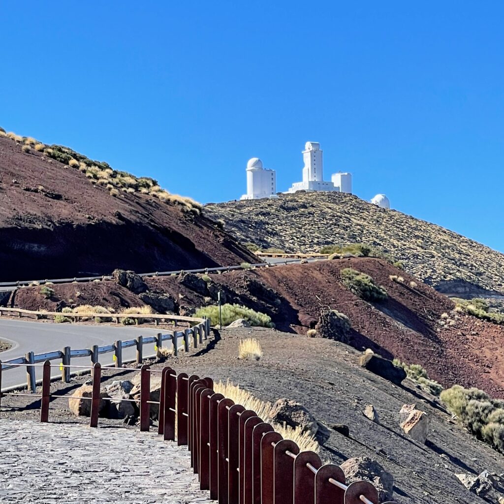 Road to Teide Observatory with white domes on a volcanic ridge — clear blue sky, Tenerife National Park.